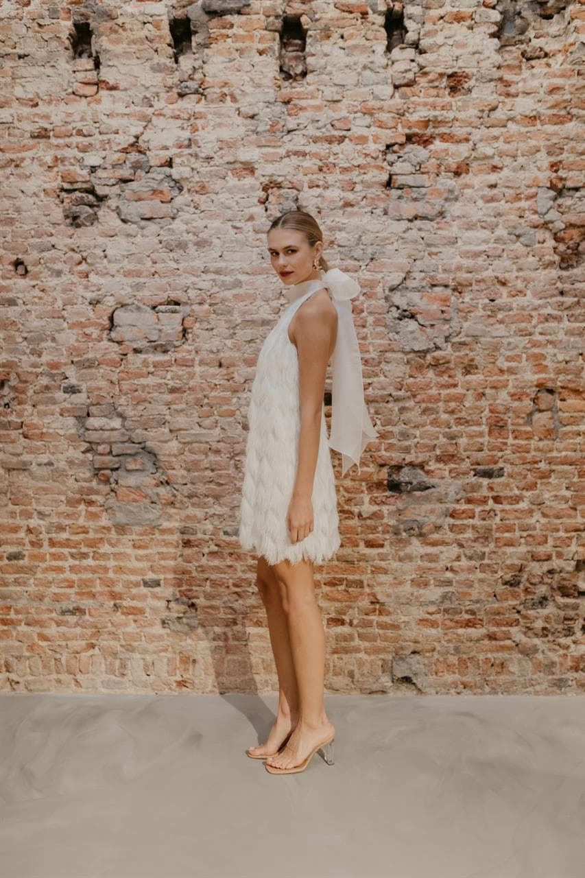 bruid met korte trouwjurk met franjes en halter voor tweede look op de bruiloft